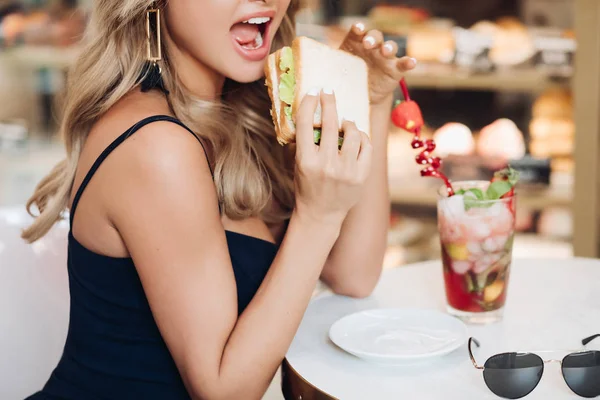 Mittlere Nahaufnahme Portrait der schönen jungen Modefrau beißt frische appetitliche Sandwich — Stockfoto