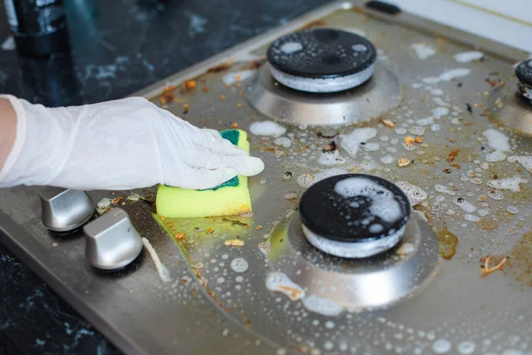 Rukavice pro domácí ženy čištění znečištěných kamen po vaření pomocí houbičky k mytí — Stock fotografie