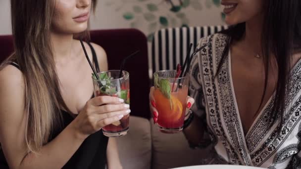 Крупным планом две гламурные подружки звенят стаканами со свежим коктейлем и пьют вместе — стоковое видео