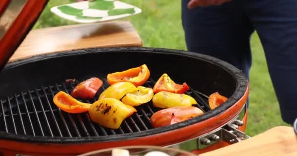 Mannelijke hand braden verse sappige zoete peper slice op barbecue draaien groenten met behulp van Tang — Stockvideo