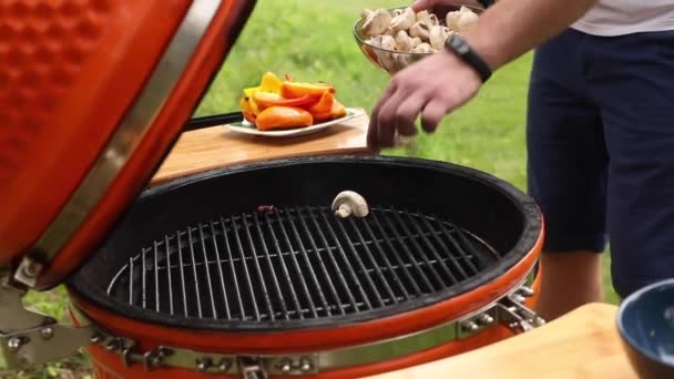 Uitzicht vanaf de zijkant van de man putting champignons op grill — Stockvideo