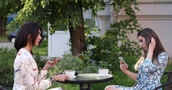 Two happy woman friend enjoying drinking coffee in outdoor cafe medium long shot