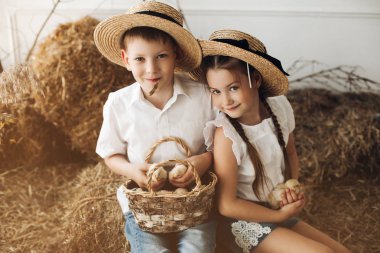 Küçük civciv tutmak saman şapkalı erkek ve kız kardeşi