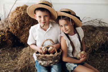 Küçük civciv tutmak saman şapkalı erkek ve kız kardeşi