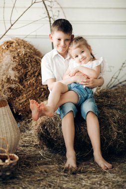 Beyaz gömlekli yakışıklı çocuk dizlerinin üzerinde güzel kız kardeşi tutarak.