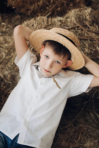 酷男孩躺在干草上，在村子里休息 — 图库照片