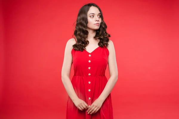 Morena en vestido rojo posando mientras brilla cayendo alrededor —  Fotos de Stock