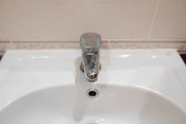 Dirty stainless bathroom tap.Bathroom tap and ceramic sink. — Stock Photo, Image