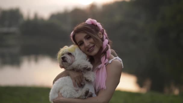 Женщина с двумя большими косичками держит собаку на руках — стоковое видео