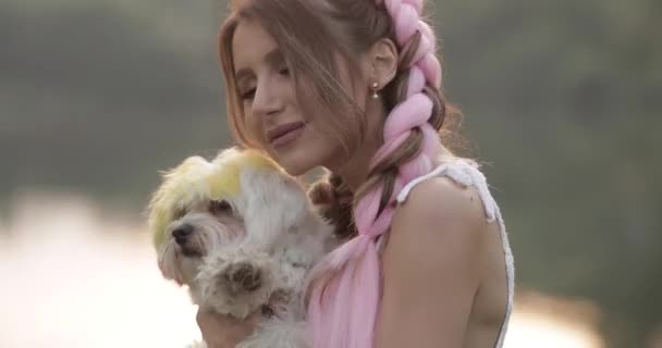 Женщина с двумя большими косичками держит собаку на руках — стоковое видео