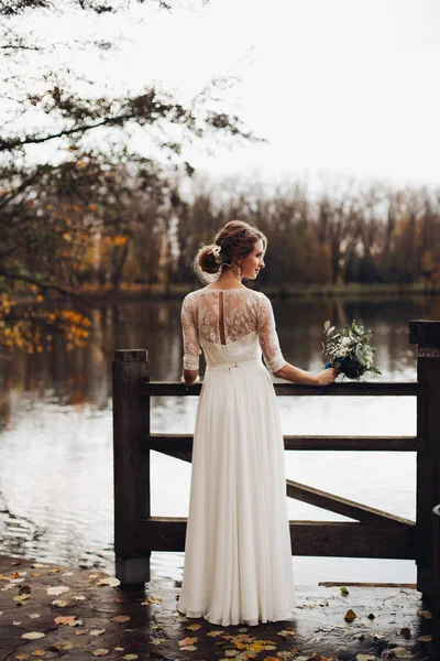 エレガントな花嫁が白いウェディング ドレス湖・ ブーケ. — ストック写真