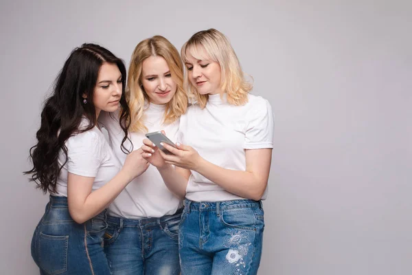 Три друзі в білій сорочці і джинсах дивляться на телефон — стокове фото