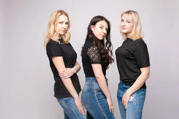 Grupo de joven amiga sonriente abrazándose posando mirando a la cámara en el fondo blanco del estudio — Foto de Stock