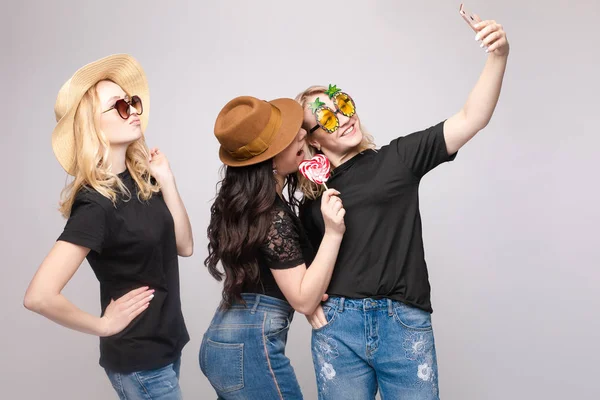 Smiling female friend wearing funny mask hat and eyeglasses posing taking selfie using smartphone — Stock Photo, Image