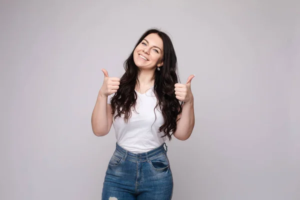 Positiv blondin i vit skjorta och jeans som visar tummen upp — Stockfoto