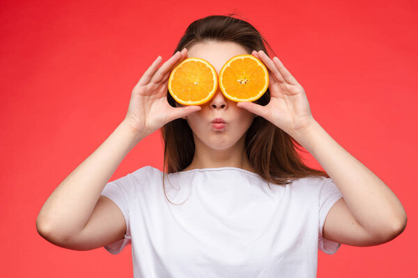 Funny fashionable girl with hairstyle holding oranges on eyes.