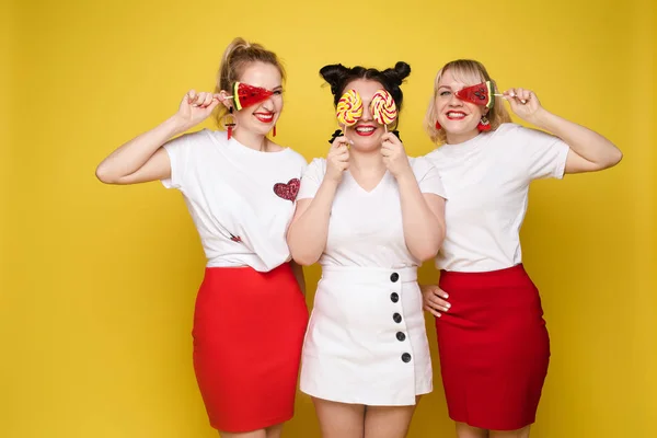 Groupe belle fille amie se détendre ensemble posant avec des bonbons colorés sucrés au studio jaune — Photo