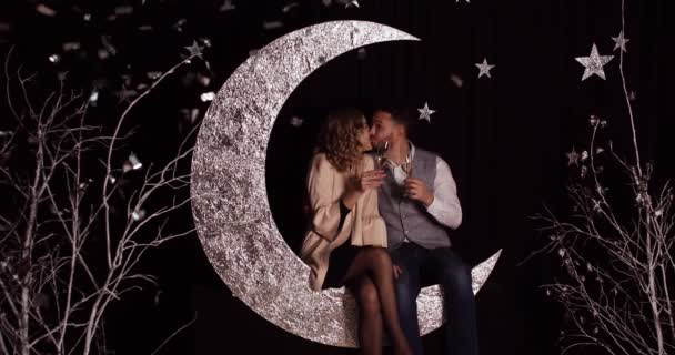 Chritmas pareja romántica. Los amantes se sientan en una luna decorativa de plata . — Vídeos de Stock