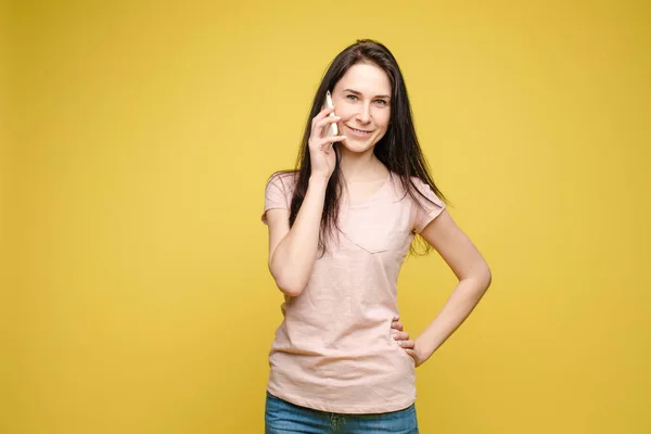 Snygg ung flicka i starkt ljus klänning pratar med telefon — Stockfoto