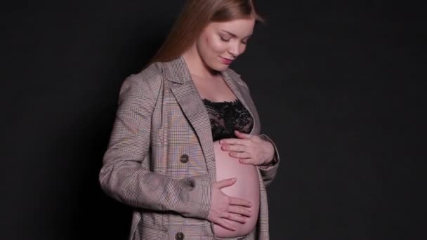 Mooie zwangere vrouw in geregen zwarte beha en jas. — Stockvideo