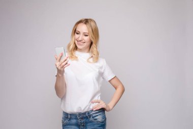 Güzel kız cep telefonunu işaret ediyor. Güzel beyaz bir kızın stüdyo portresi.