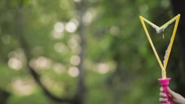 Kadın el üfleme parıldayan sabun hava kabarcık yakın çekim yavaş hareket tutarak