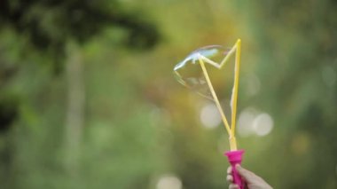 Kadın el üfleme parıldayan sabun hava kabarcık yakın çekim yavaş hareket tutarak