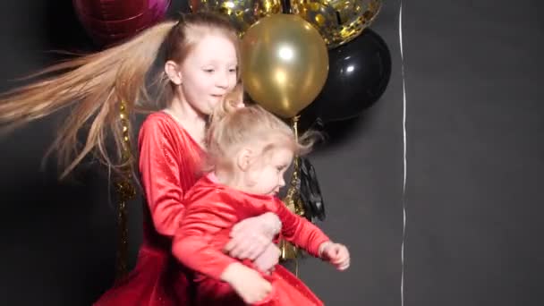 Preciosa niña feliz saltando con confeti y globos de aire en el fondo . — Vídeo de stock