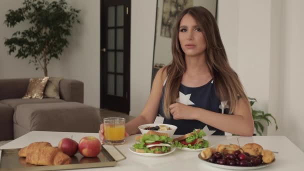 Красивая молодая женщина сидит на столе с аппетитным вкусный завтрак средний выстрел — стоковое видео