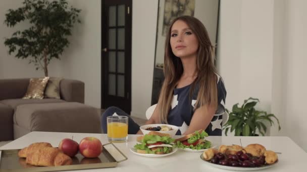 Красивая молодая женщина сидит на столе с аппетитным вкусный завтрак средний выстрел — стоковое видео