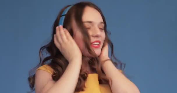 Young girl in yellow shirt and headphones listening music — Stock Video