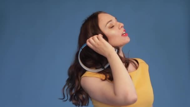 Young girl in yellow shirt and headphones listening music — Stock Video