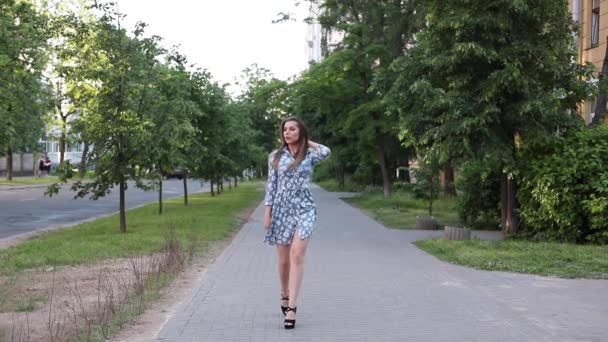 Prachtige vrouw in jurk wandelen naar camera in de straat. — Stockvideo