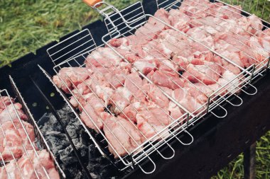 Izgarada çiğ et. Çiğ et birçok parça üst görünümü barbekü için ızgara üzerinde pişiriliyor. Barbekü eti açık havada ızgarada hazırlanıyor.