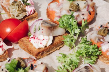 Ringa balığı ile lezzetli kanepeler. Taze ringa balığı, siyah susam, gevrek ekmek üzerine krem peynir ile lezzetli kanape veya sandviç Makro.