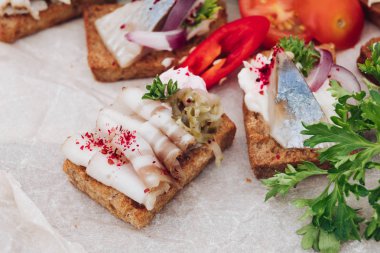 Ringa balığı ile lezzetli kanepeler. Taze ringa balığı, siyah susam, gevrek ekmek üzerine krem peynir ile lezzetli kanape veya sandviç Makro.