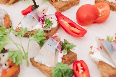Ringa balığı ile lezzetli kanepeler. Taze ringa balığı, siyah susam, gevrek ekmek üzerine krem peynir ile lezzetli kanape veya sandviç Makro.