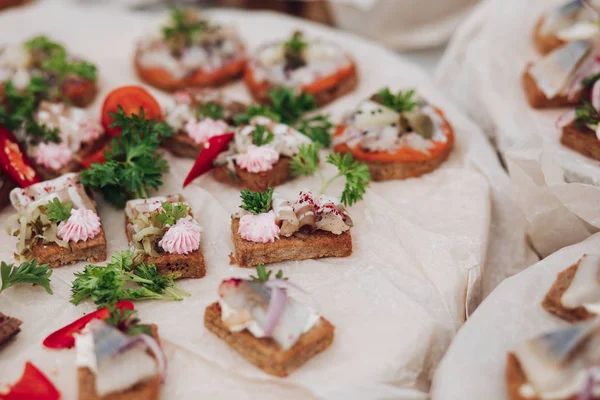 Delicious sandwiches with herring and onion.Close-up of tasty crispy sandwiches or canapes with cream cheese, onion and herring on the top. Parsley and chilli pepper on the platter. — Stock Photo, Image