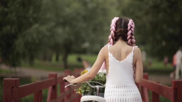 Vista desde la parte posterior de la chica en vestido blanco bicicleta de montar en el parque — Vídeos de Stock