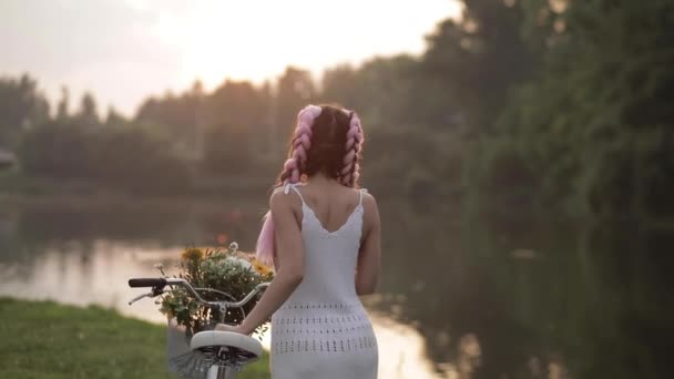 Bella ragazza con acconciatura elegante a piedi con la bicicletta nel parco . — Video Stock