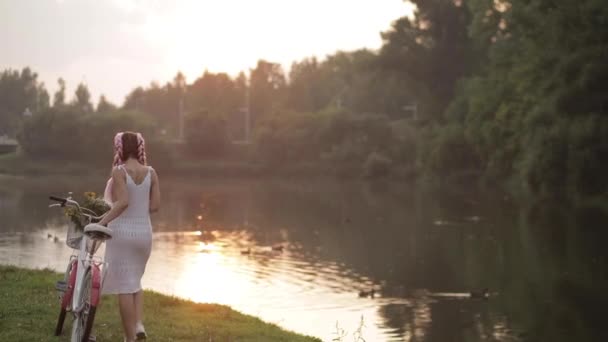 Bella ragazza con acconciatura elegante a piedi con la bicicletta nel parco . — Video Stock