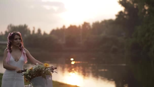 호수 근처 공원에서 타고 흰색 드레스에 매력적인 여자 — 비디오