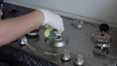 Yakın çekim kadın el giyen eldiven temizliği mutfak sobayı sünger kullanarak