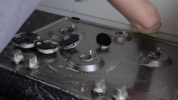 Close-up female hand wearing gloves cleaning kitchen stove hob using sponge — Stock Video