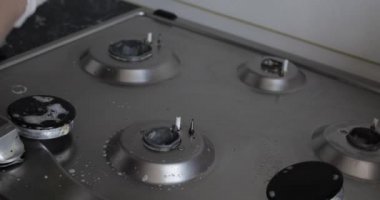 Yakın çekim kadın el giyen eldiven temizliği mutfak sobayı sünger kullanarak