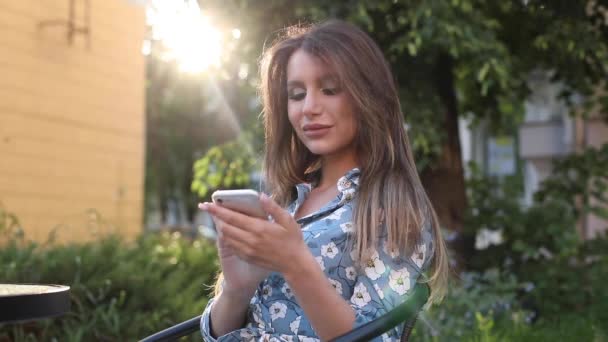 Mujer bonita feliz navegando móvil en la cafetería al aire libre . — Vídeos de Stock