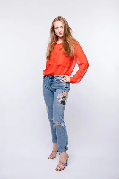 Menina de blusa vermelha e jeans posando em fundo isolado — Fotografia de Stock