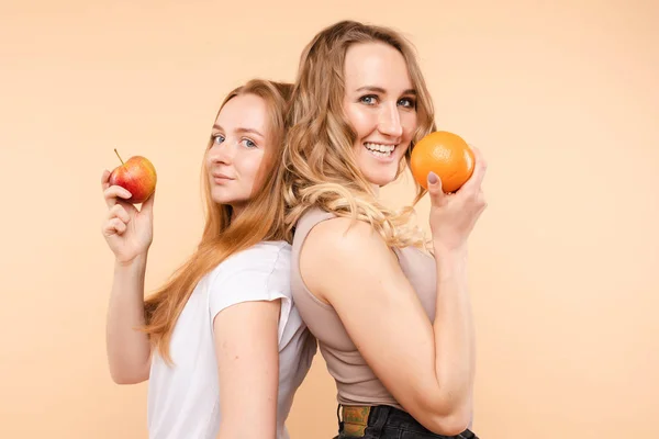 Pretty girlfriends smiling with an orange.Healthy food concept. — Stockfoto