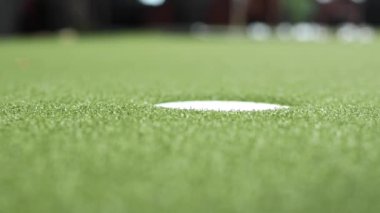 Yakın çekim profesyonel spor golf oynarken deliğe küçük golf topu koyarak