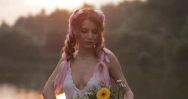 Güzel çiçek buketi koklayan beyaz elbiseli kadın